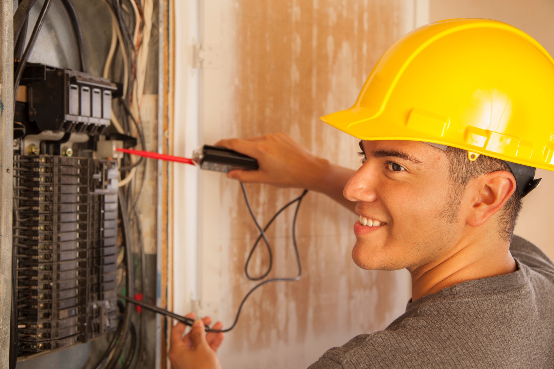 Construction: Blue collar worker, electrician repairs circuit breaker.